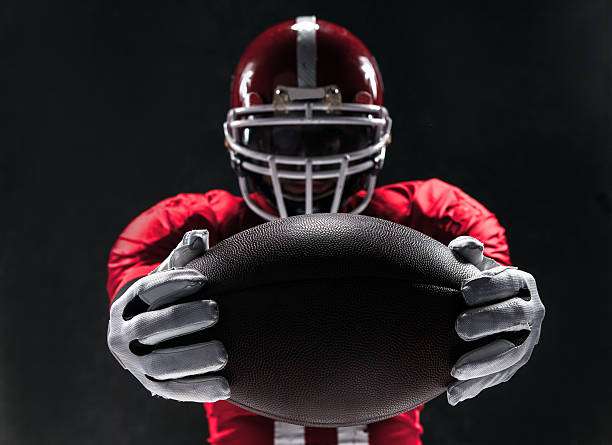 A football player wearing football gloves and holding the ball