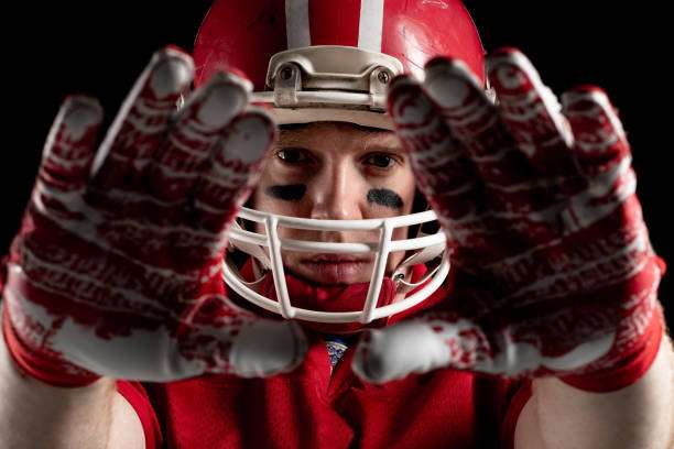 Close-up of football player wearing red and white football gloves.