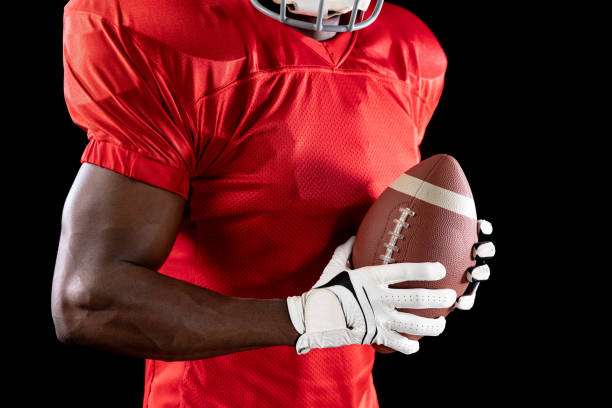 American football player in red jersey wearing white football gloves holding the ball.