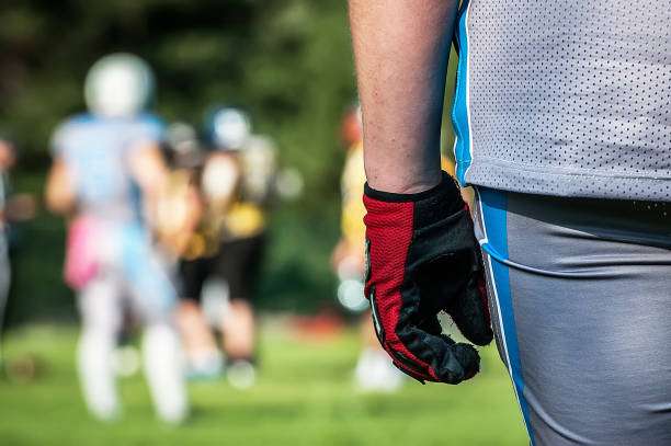 Close-up of a football player wearing a red and black pair of football gloves.