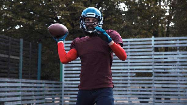 Man in helmet and football gloves throwing a football.