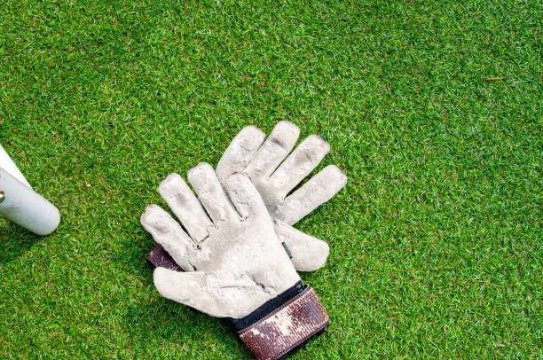Used, well-worn football gloves lying on vibrant green grass field.